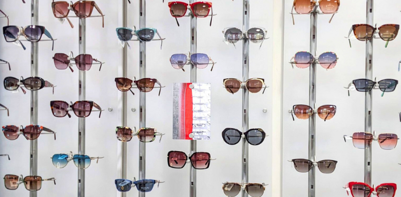 A display of sunglasses in a range of styles and colors at an opticians.]