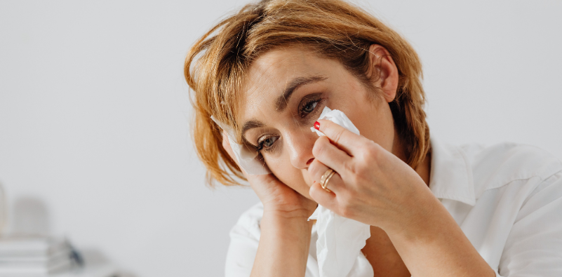 Woman wiping tears from her irritated eyes